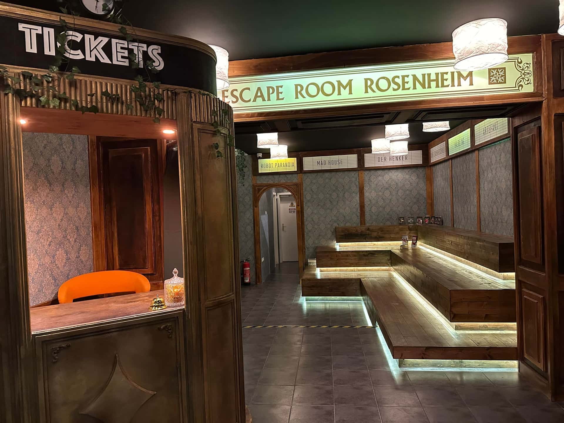 Lobby mit Ticketschalter und beleuchteten Sitzbänken im Escape Room Rosenheim