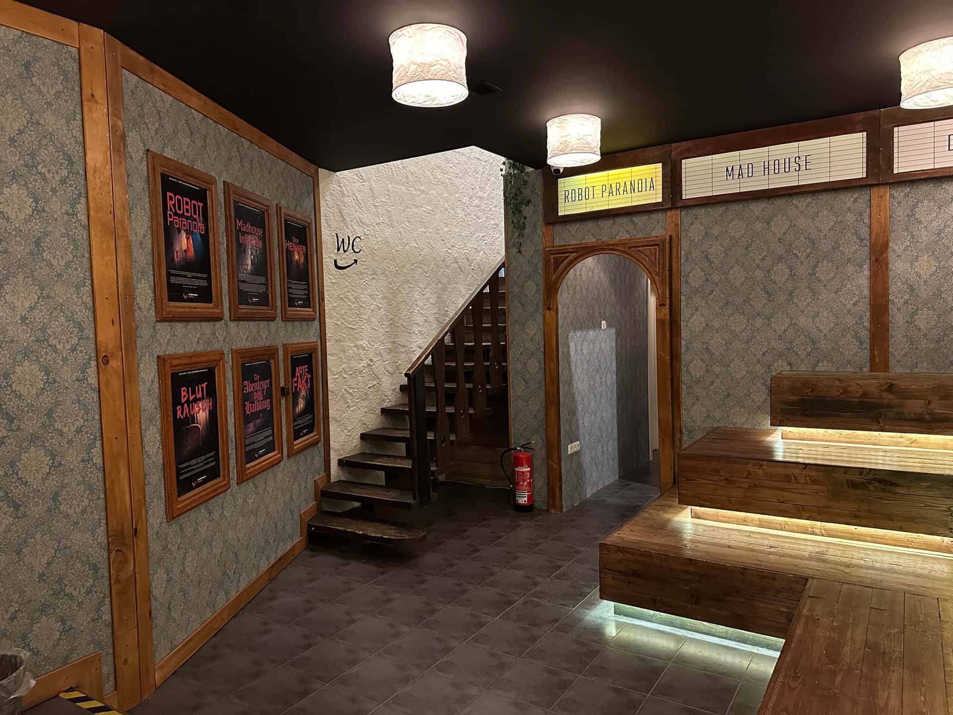 Lobby mit Treppe, Raumplakaten und Durchgang zu den Spielräumen im Escape Room Rosenheim