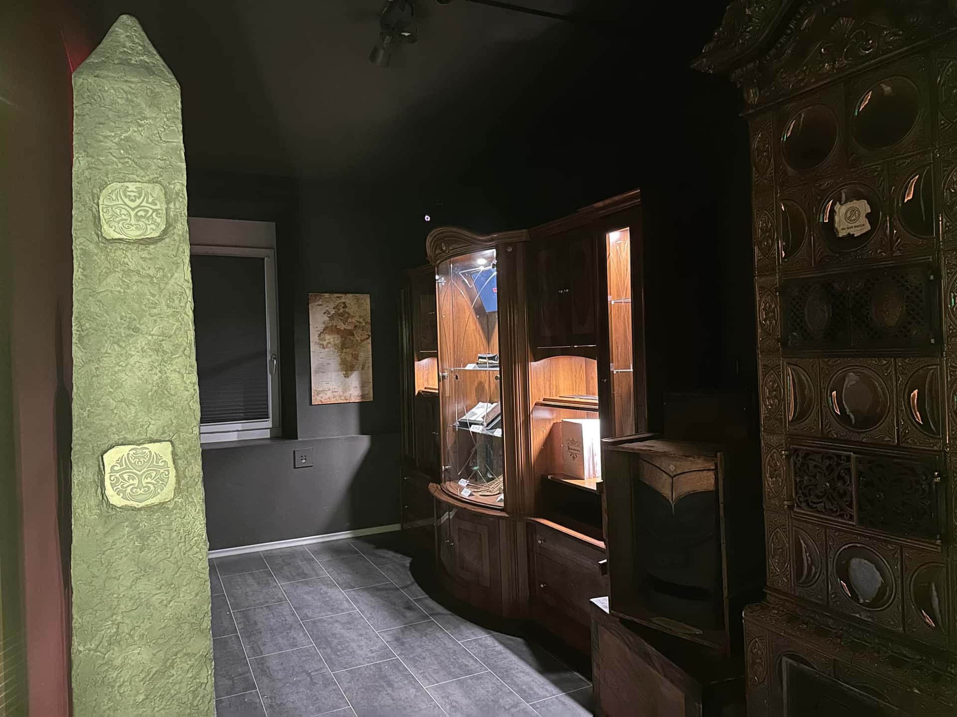 Steinerner Obelisk vor Museumsvitrinen im Lagerraum im Escape Room Artefakt in Rosenheim