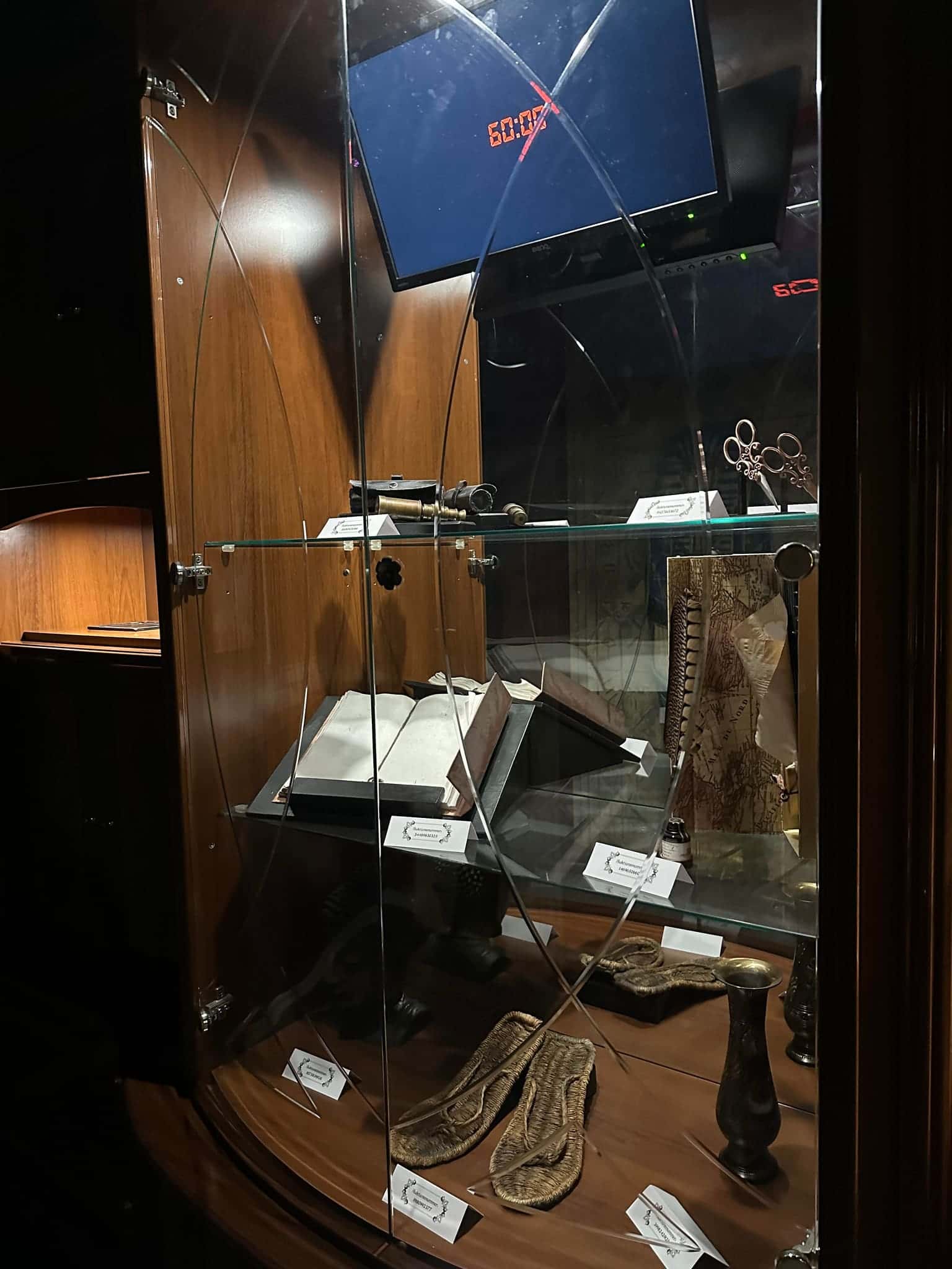 Museumsvitrine mit altem Buch, Sandalen und Fundstücken im Escape Room Artefakt in Rosenheim