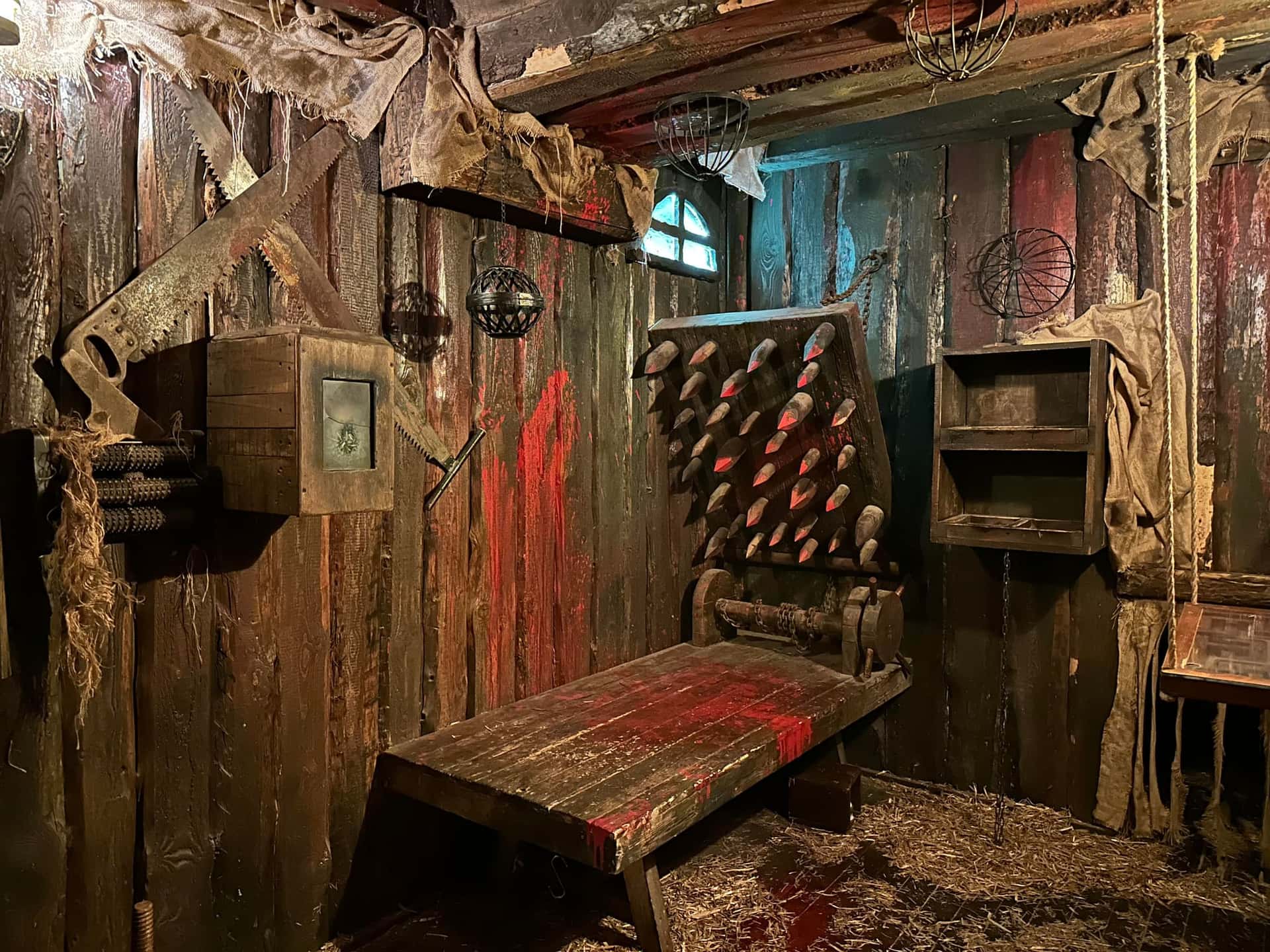 Folterkammer mit Stachelbrett, blutverschmierter Holzbank und Säge an der Wand im Escape Room Der Henker in Rosenheim