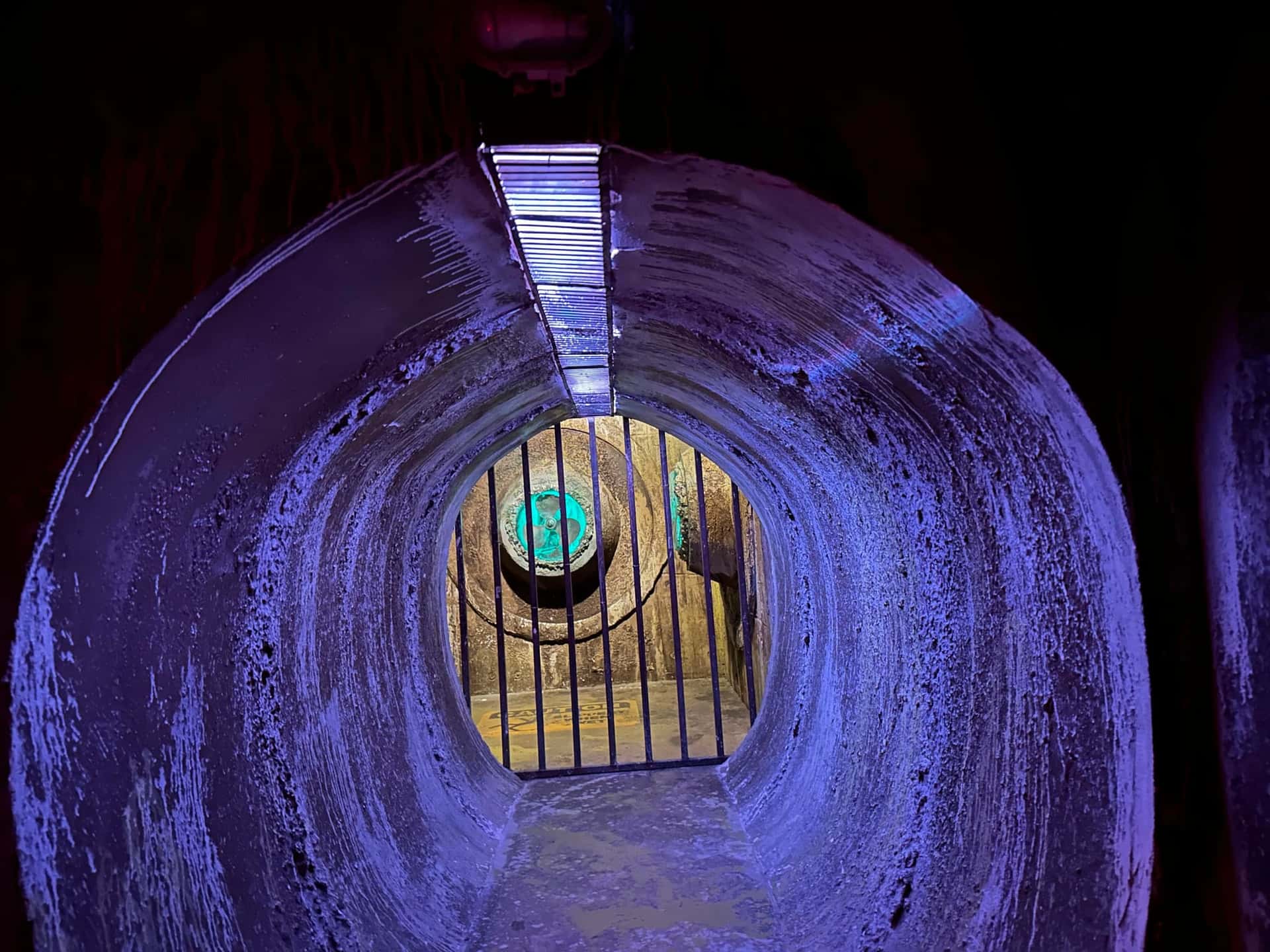 Violett beleuchteter Tunnel mit Gitter und Ventilator im Escape Room Robot Paranoia in Rosenheim