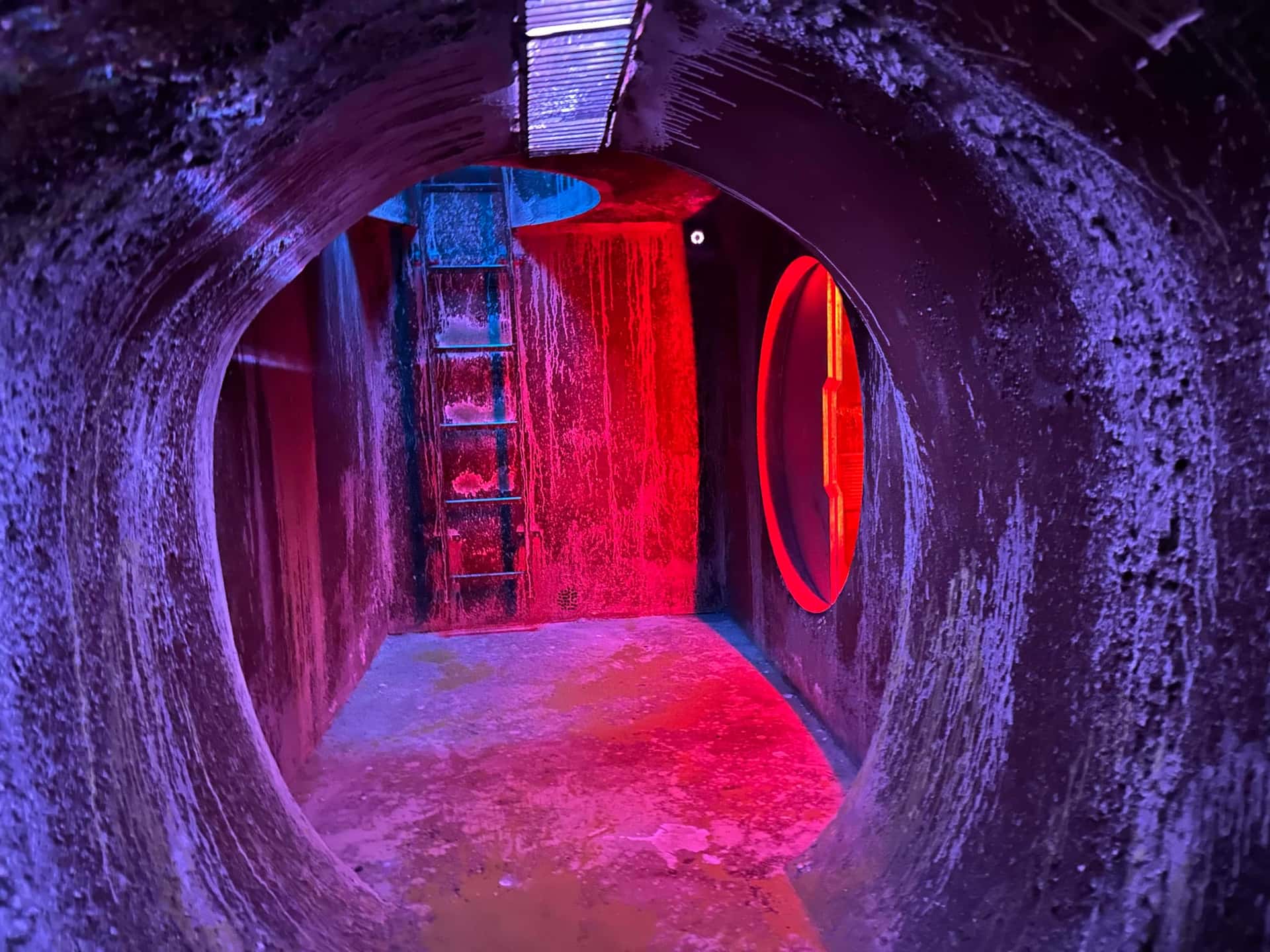 Tunnel mit Blick in einen rot beleuchteten Raum im Escape Room Robot Paranoia in Rosenheim