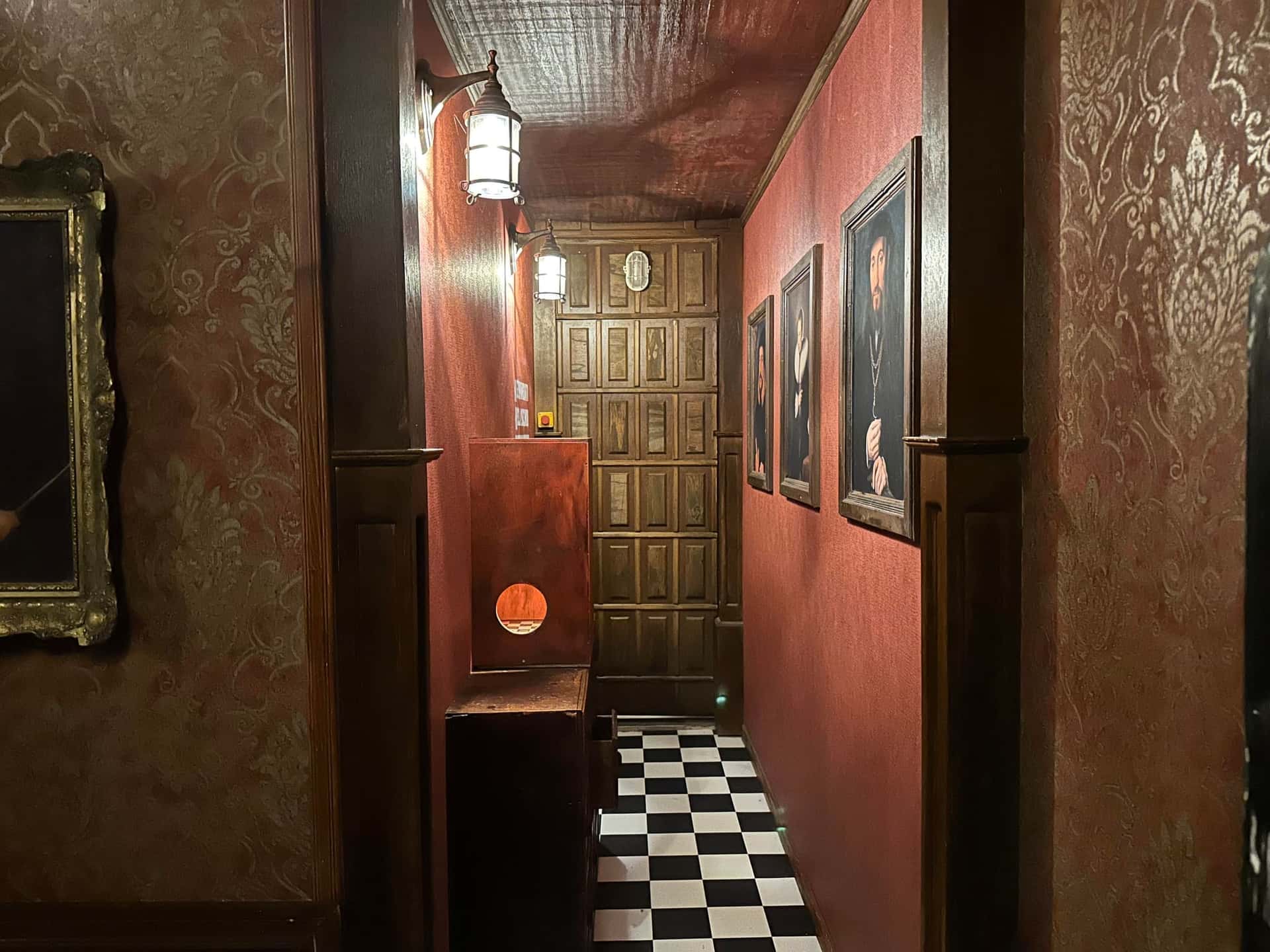 Schmaler Gang mit Ahnenporträts und Schachbrettboden im Escape Room Die Zauberschule in Rosenheim