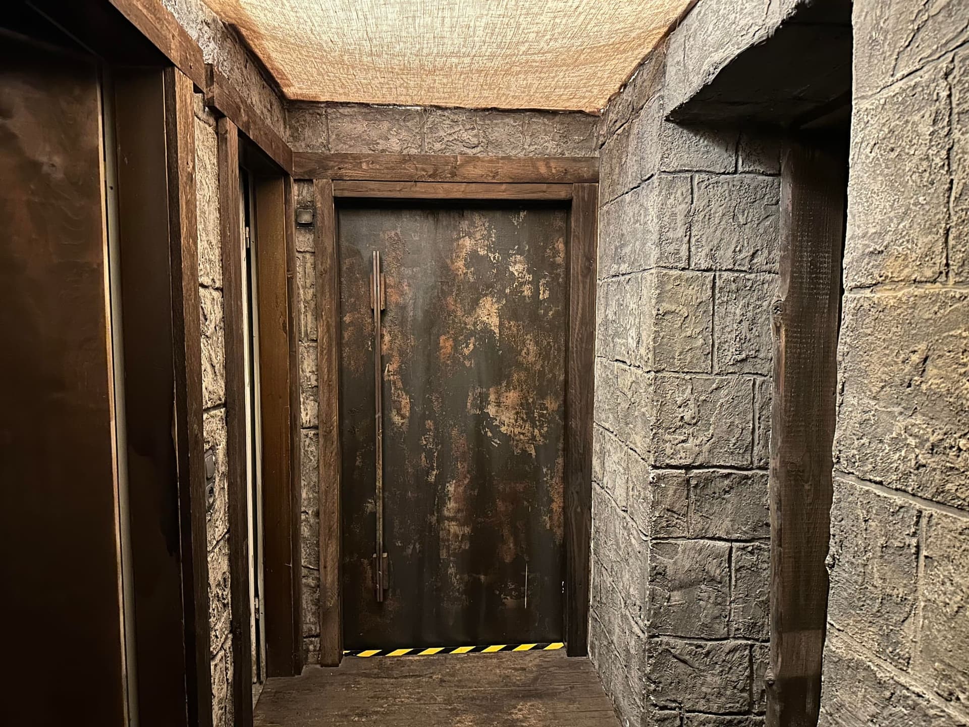 Steinerner Flur mit Metalltür zu den Spielräumen im Escape Room Rosenheim